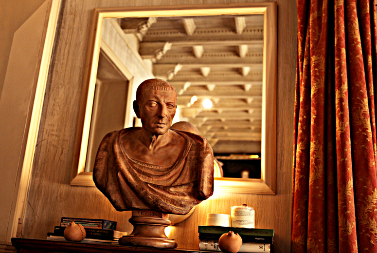 Escultura de Cicerón en una repisa con un espejo detrás que refleja una habitación.