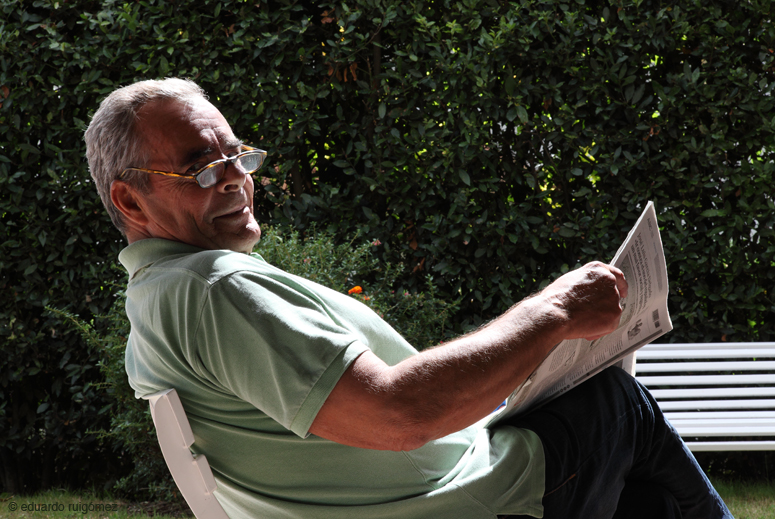 Hombre leyendo el periódico gira la cabeza a cámara.