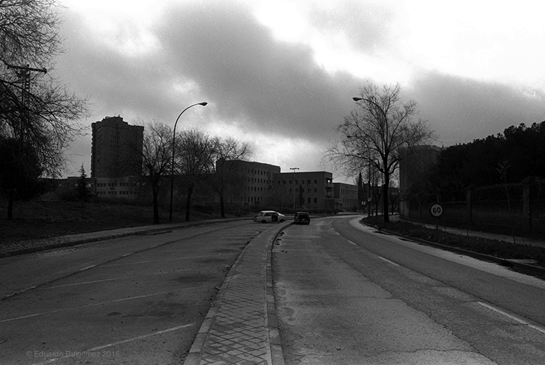 Calle oscura con coches abandonados.