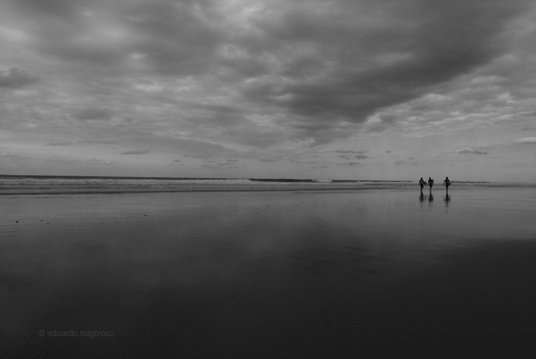 Tres surfistas en la orilla del mar..