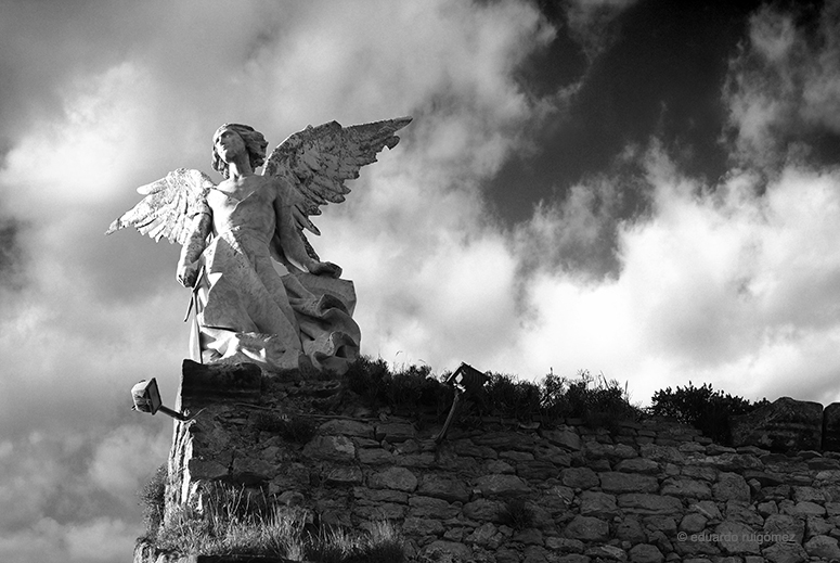 Escultura de un ángel con espada sobre un muro del cementerio de Comillas, Cantabria.