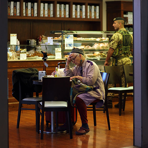 Una señora toma un café mientras un soldado echa un vistazo por el local.