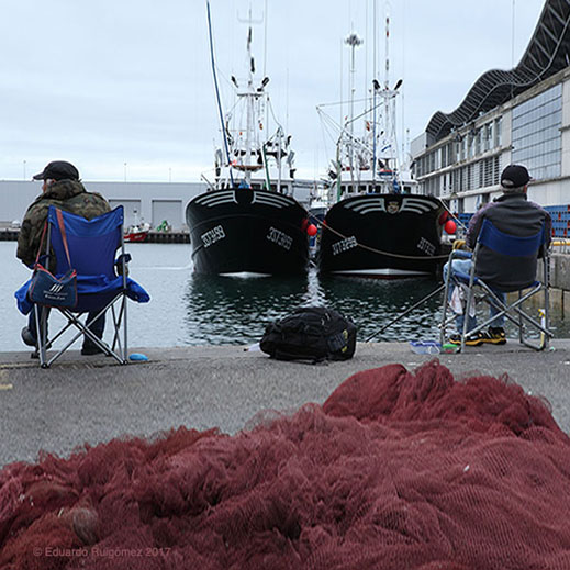Dos pescadores en un puerto.