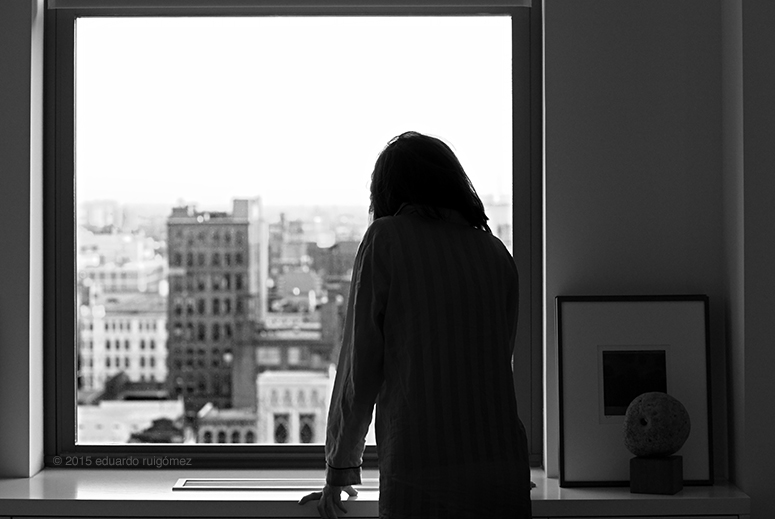 Mujer mirando desde una ventana la ciudad al amanecer .
