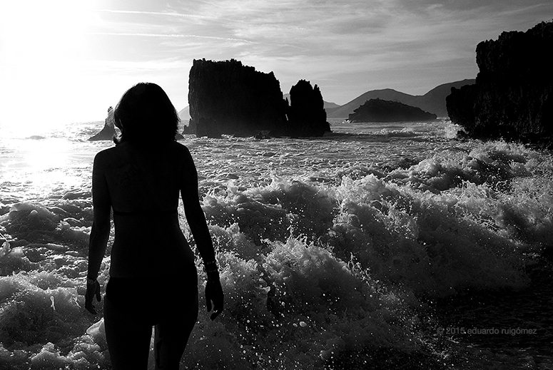 Una mujer se baña en una playa al amanecer.