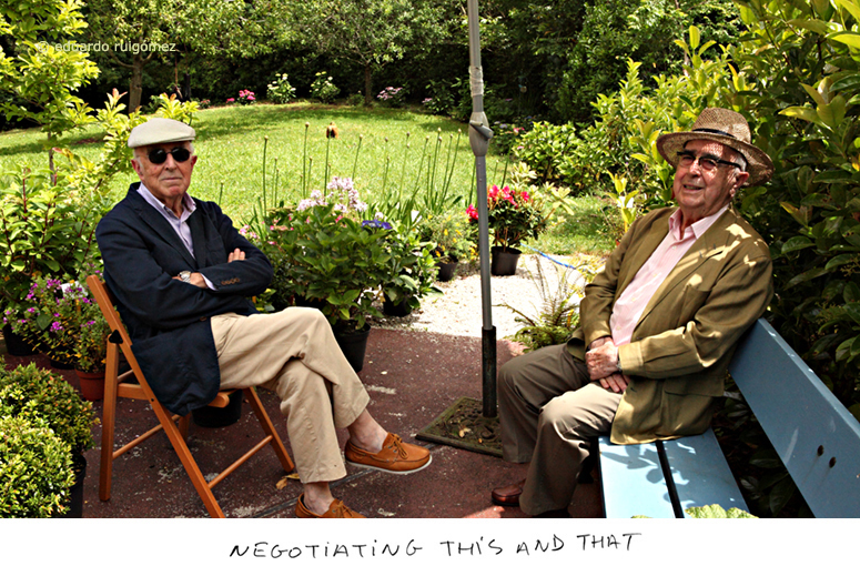 Dos personas sonrientes en un jardín sentados uno frente al otro.