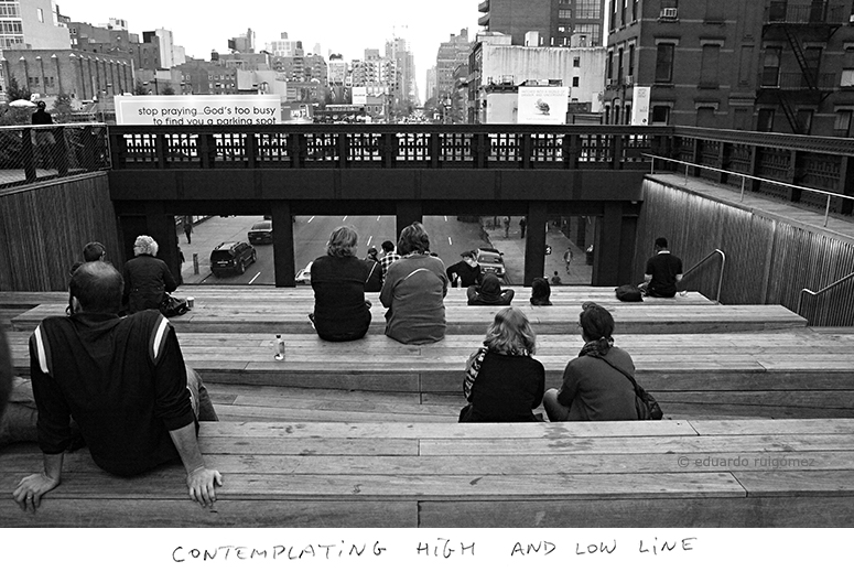Gente sentada en una plataforma de madera escalonada con vistas a una calle y de un tramo de una línea del suwbay.