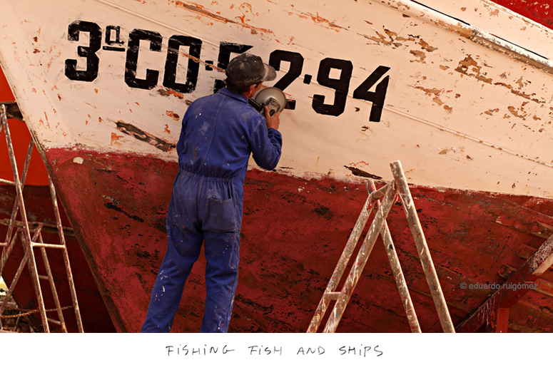 Un operario repara el casco de un barco pesquero.